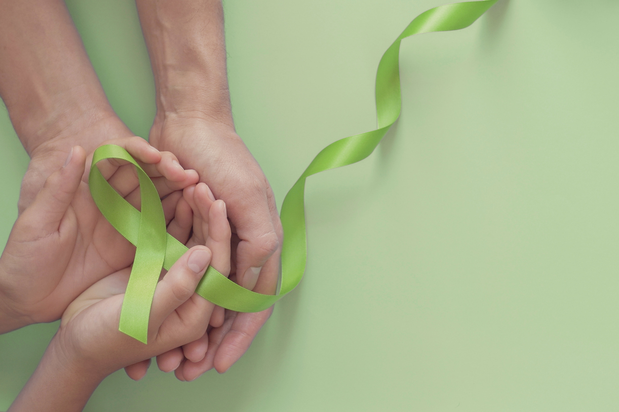 two pairs of hands holding mental health awareness ribbon as an expression of the importance of mental health awareness